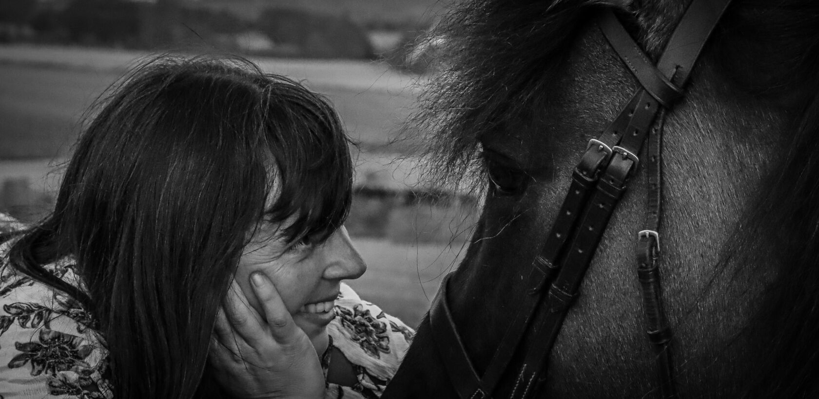 Lady lying on straw bale in field at harvest admiring view with highland pony