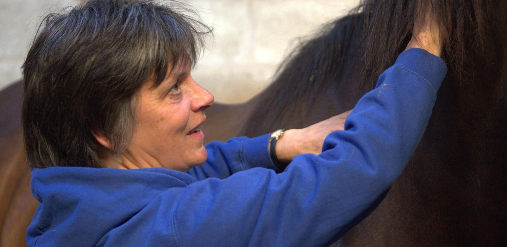 Woman standing next to horse in stable